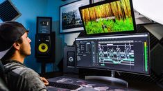 a man sitting in front of a computer monitor with sound recording on the wall behind him