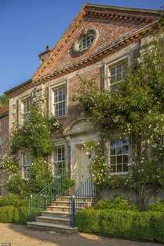 an old brick building with many windows and steps leading up to the front door is shown