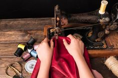 a woman is sewing on an old sewing machine with red fabric and other craft supplies