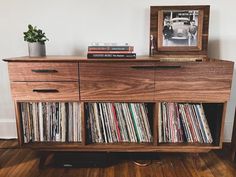 an old record player sits on top of a wooden cabinet with records in the drawers