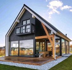 a house that is on the grass with a deck in front of it and lots of windows