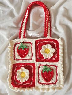 a crocheted strawberry purse with four squares on the front and two flowers on the back