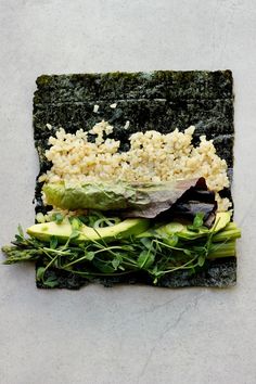 a square piece of food that is on top of some kind of paper with rice and veggies in it