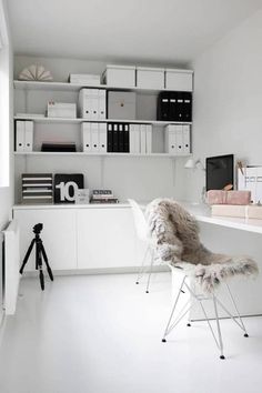 an office with white walls and shelves filled with books, papers, and other items