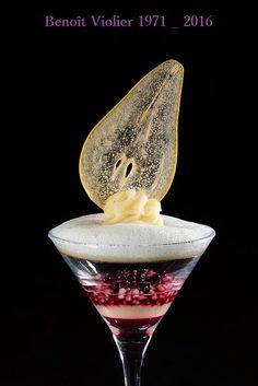 a dessert in a martini glass topped with whipped cream and berries