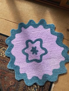 a blue and purple rug on the floor next to a rug with a flower design