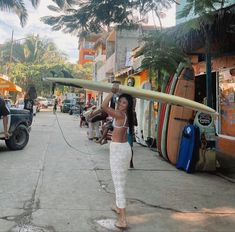 a woman carrying a surfboard down a street