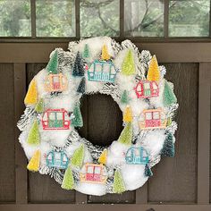 a wreath is hanging on the front door with trees and houses painted on it, next to a fire hydrant