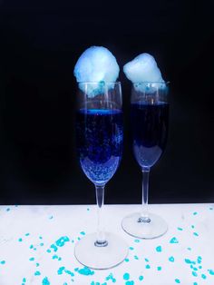 two wine glasses filled with blue liquid and ice