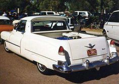 an old white car parked in a parking lot