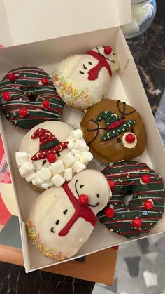 six decorated donuts in a box on a table