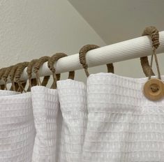 white curtains hanging on a rod in front of a ceiling fan with rope attached to it