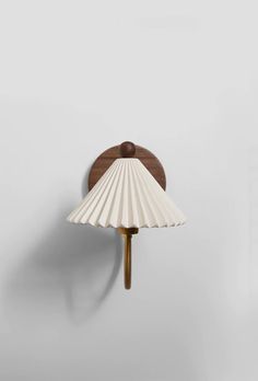 a wall lamp with a wooden base and white shell shade on the back of it