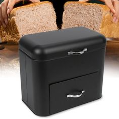 a black bread bin with two slices of bread in it and someone grabbing one slice