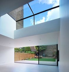 an empty room with glass walls and skylights on the top floor that overlooks a backyard