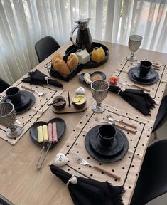 the table is set with black plates and silverware