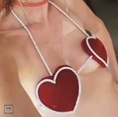 a woman wearing red and white necklaces with two hearts on the back of her chest