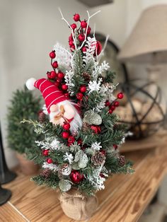 a small christmas tree with santa claus on top and pine cones in the bottom, sitting on a wooden table