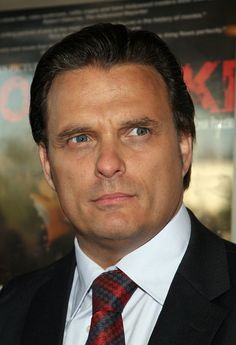 a close up of a person wearing a suit and tie in front of a movie poster