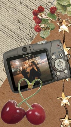 a digital camera sitting on top of a table next to two cherries and stars