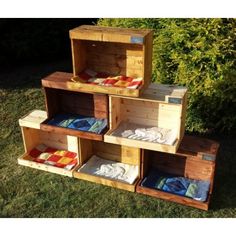 four wooden crates stacked on top of each other in the grass with blankets and pillows