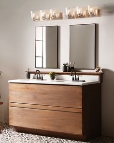 a bathroom vanity with two mirrors and lights above it, next to a potted plant