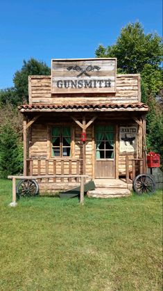 an old fashioned wooden building sitting on top of a lush green field