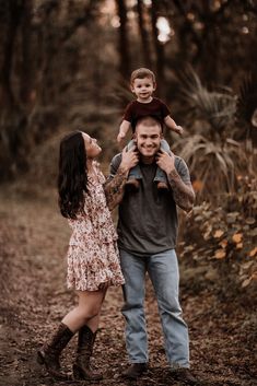 a man and woman holding a small child in the woods