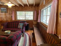 a living room filled with furniture and wood paneling on the walls next to a window