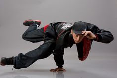 a man is doing a handstand on one leg and wearing a black hat