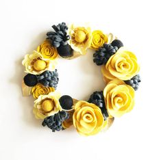 a wreath made out of felt flowers on a white background with black and yellow accents