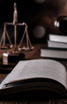 an open book sitting on top of a wooden table next to a judge's scale