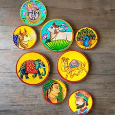 six colorfully painted plates sitting on top of a wooden table