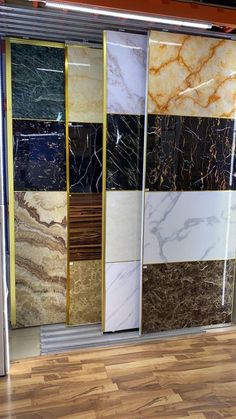 several different colors and sizes of marble tiles on display in a store front window with wood flooring