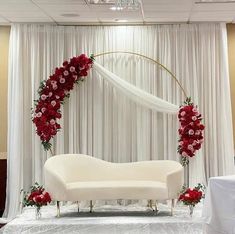 a white couch sitting in front of a white curtain with red flowers on the back