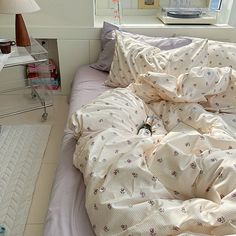 an unmade bed with white sheets and pink comforter in a small room next to a window