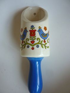 a blue and white ceramic toothbrush holder with birds on it's side, sitting on a table