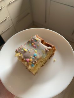 a piece of cake with frosting and sprinkles on a white plate