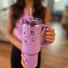 a woman holding a pink tumbler cup with stars and unicorns on the side