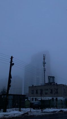 a tall building sitting in the middle of a foggy sky next to a traffic light