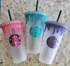 three starbucks cups decorated with swarozak and glitters on the sides, one is pink, one is blue