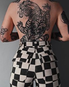 a man with tattoos on his back wearing checkered pants