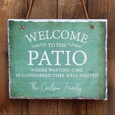 a welcome sign hanging on the side of a wooden fence that says, welcome to the patio