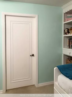 a bedroom with blue walls and a white door in the corner that leads to another room