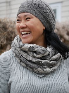 a smiling woman wearing a gray hat and scarf