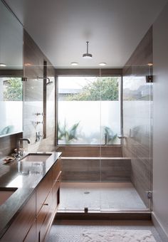 a bathroom with a large glass shower door and wooden cabinetry, along with two sinks