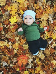 a baby is laying in leaves on the ground