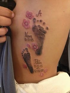 a woman's lower back tattoo with footprints and flowers