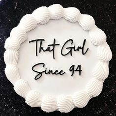 a cake with the words that girl since 94 written in black on it and surrounded by scalloped icing