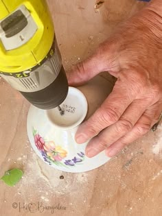 a person is using a drill to fix a plate with flowers on it and a yellow object in the background